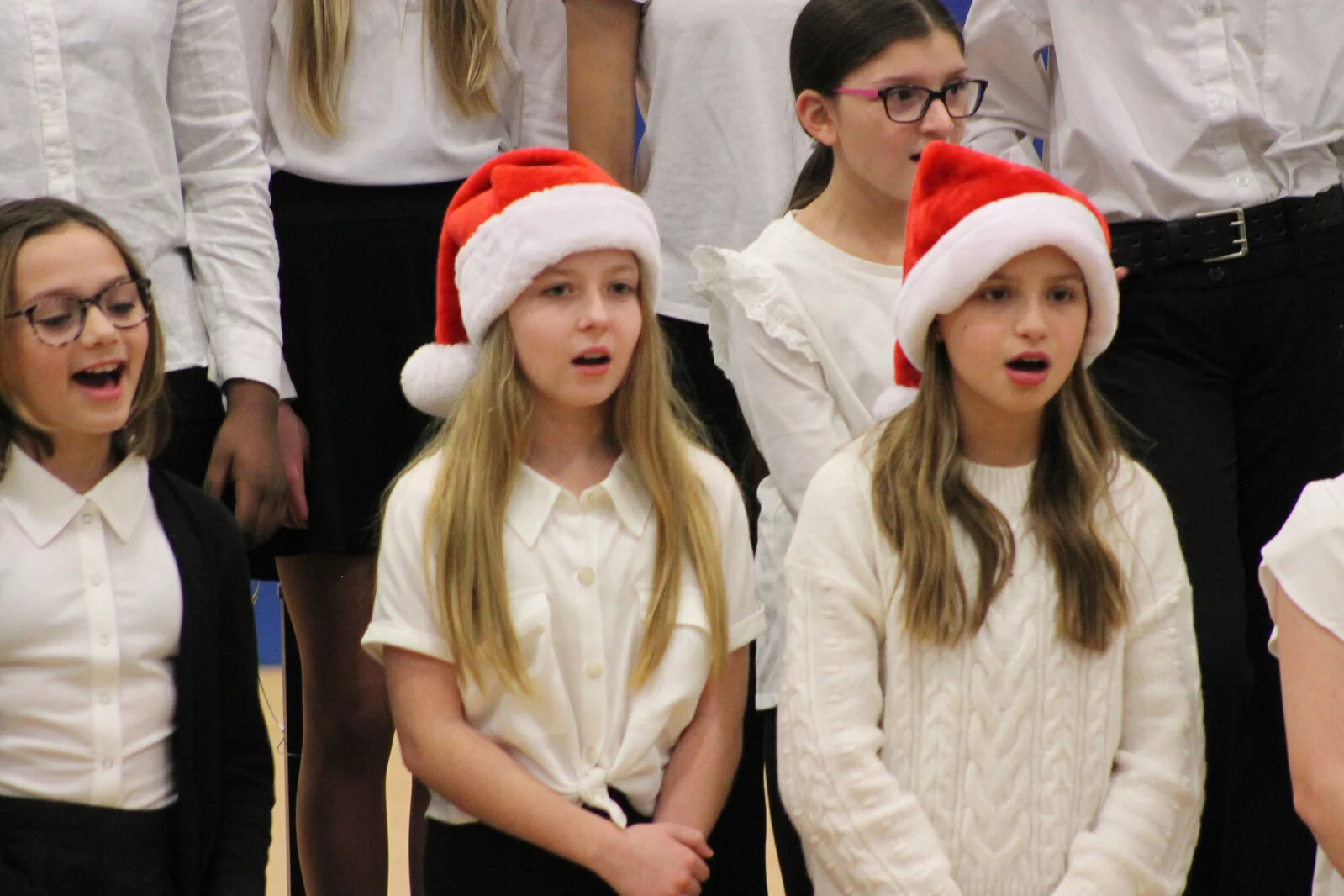 close up of two students singing with santa hats on